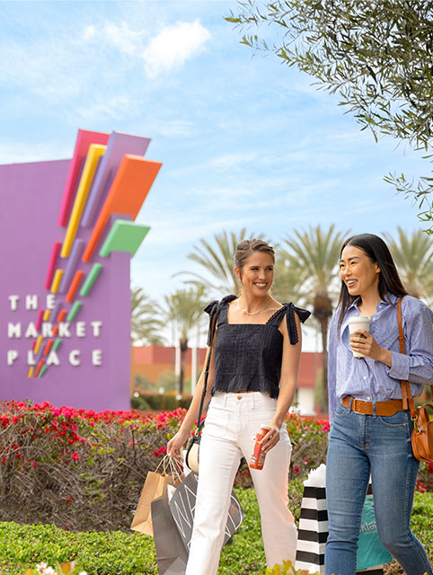  Two people walking in front of The Market Place monument sign in Tustin and Irvine