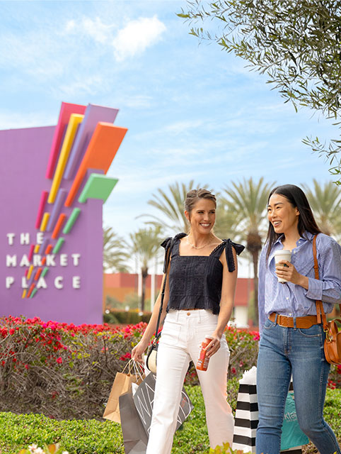  Two people walking in front of The Market Place monument sign in Tustin and Irvine